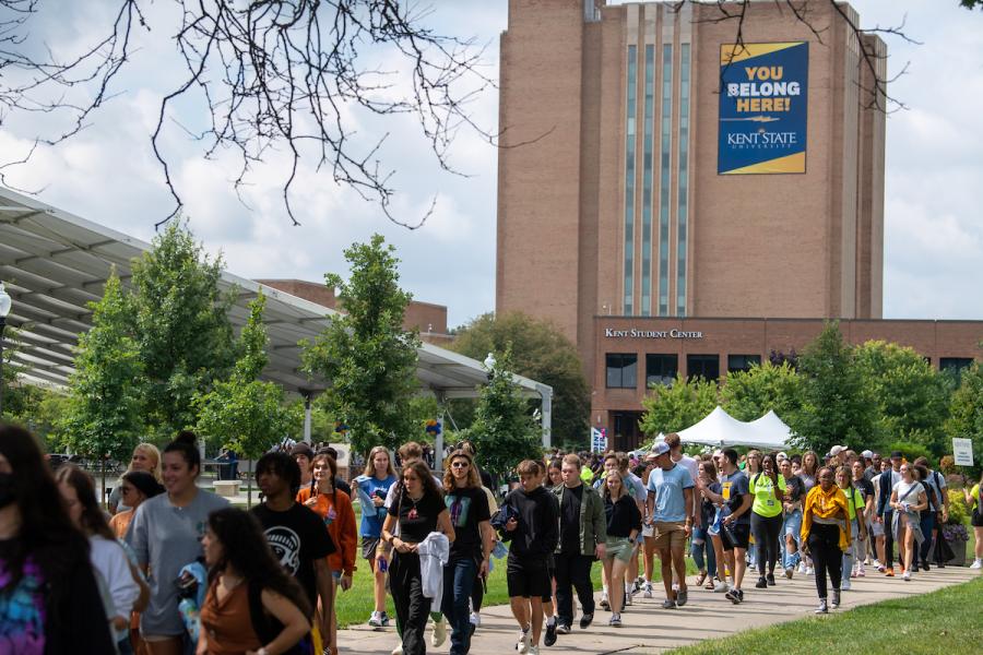 A line of first-year students walk from the MAC Center to the Student Green on Kent Campus.