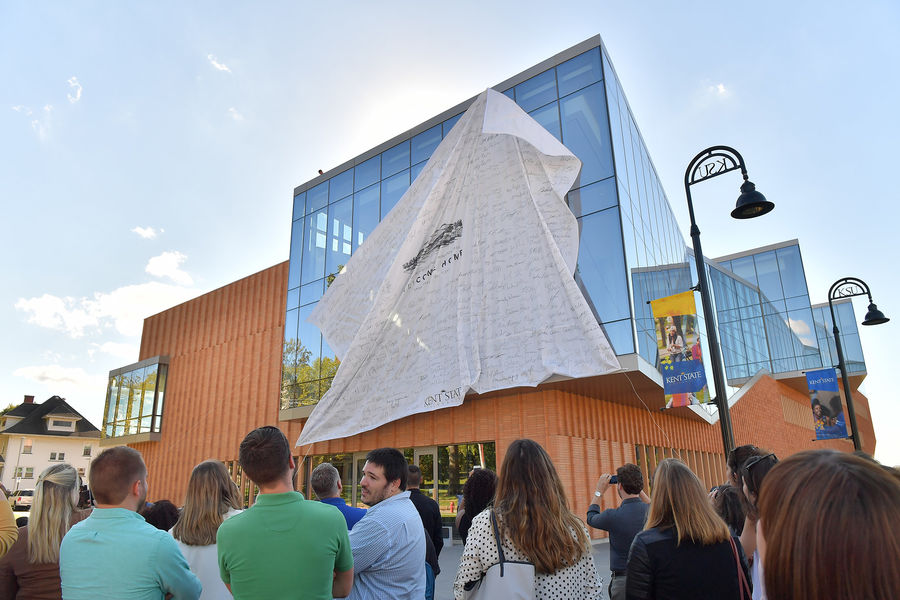 A sheet, signed by Kent State students, employees, alumni and others, is pulled down to reveal the new Center for Architecture and Environmental Design.