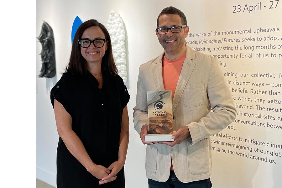 Davin Ebanks being presented the top award for the 2nd Cayman Biennial, His work of casted glass baskets are pictured on the left.