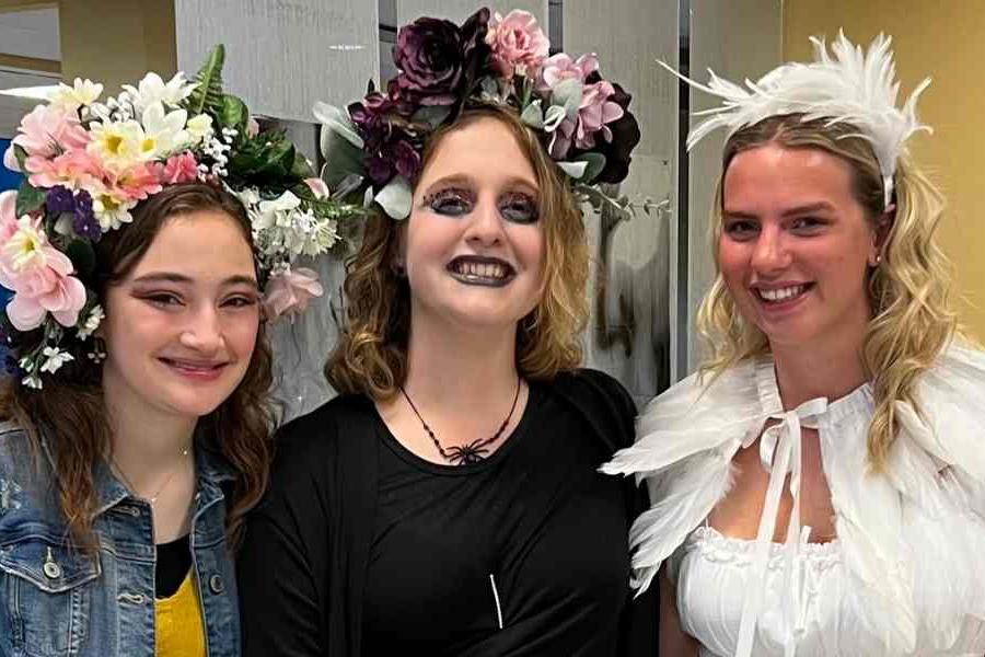 Three students dressed in halloween costumes smiling for a photo at the Kent State University Haunted Library party. 