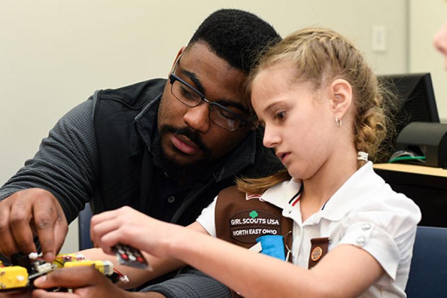 Professor helping a young girl scout with a model plane