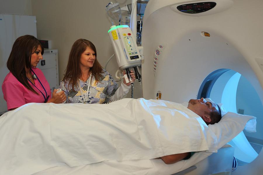 A radiologist at Robinson Memorial Hospital shows a Kent State student how to prepare a patient for a CT scan.