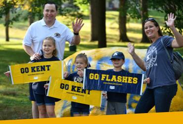 Photo of people waving at the camera, holding "Go Flashes, Go Kent" signs during homecoming parade