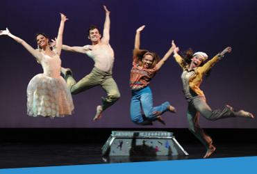Photo of students, performing in a play, jumping in the air
