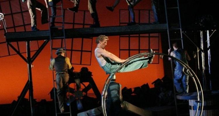 picture of Cirque Mechanics performing on a wheel with red and black background