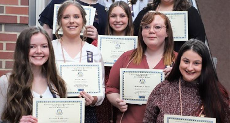 Eight nursing students holding certificates for Nursing Honor Society induction
