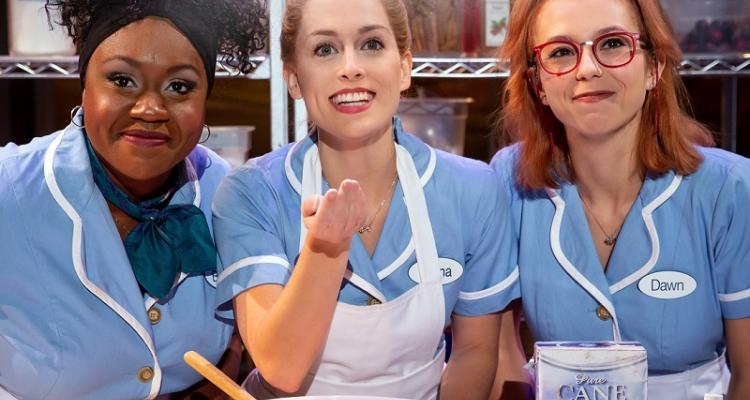 picture of the three leading stars from National Tour of Waitress wearing uniforms behind a table of baking supplies