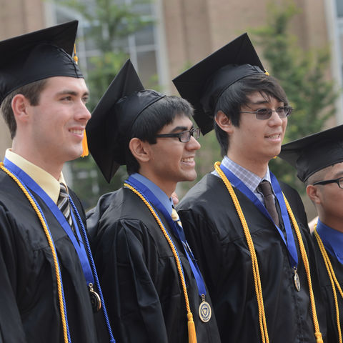 Four friends pose for a photo after the summer 2013 Commencement near the fountain in the Risman Plaza.
