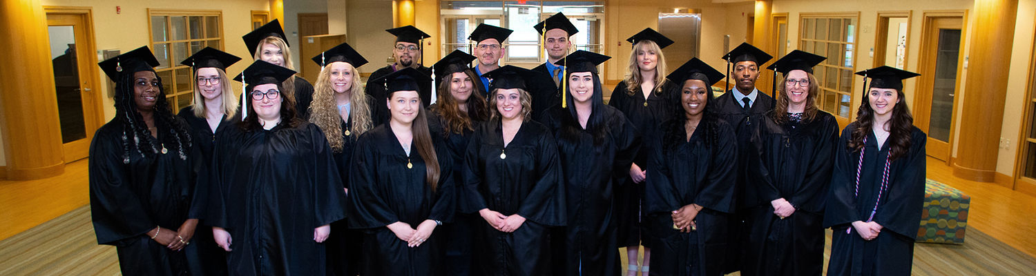 Group of students in graduation gowns standing in a room