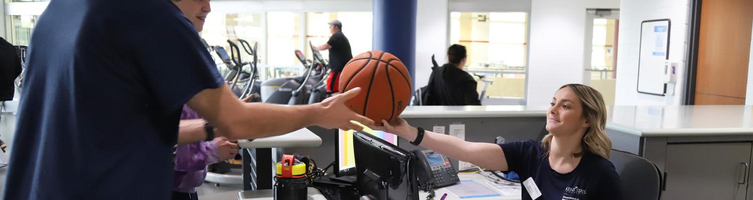 Employee Handing Out Basketball to Students