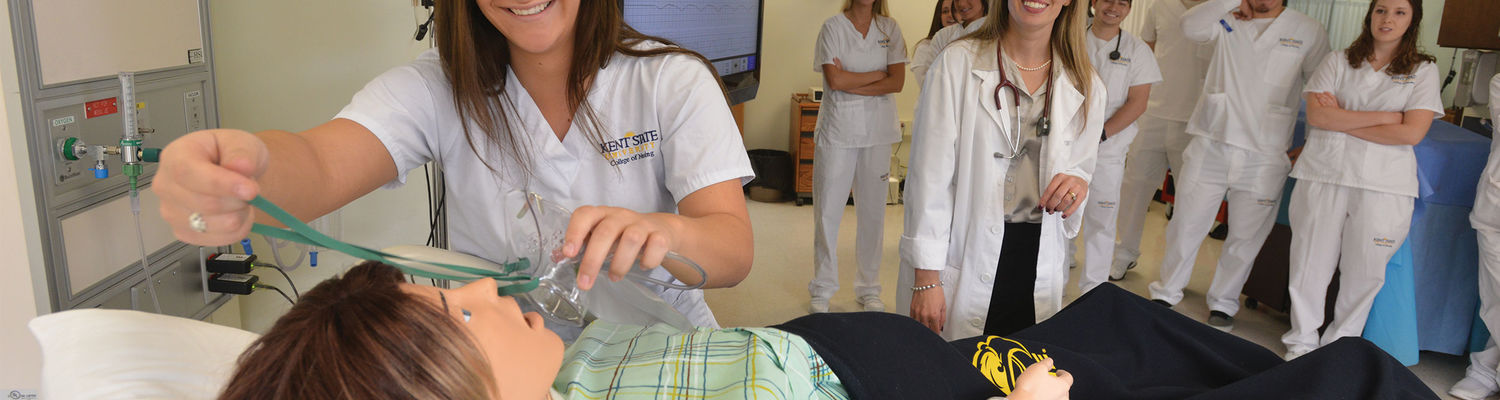 A Kent State nursing student practices putting an oxygen mask on a patient simulator