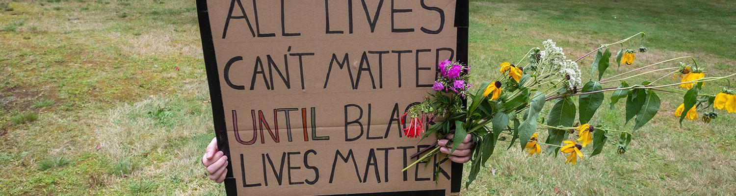 A student holding a sign that reads, "All lives can't matter until black lives matter."