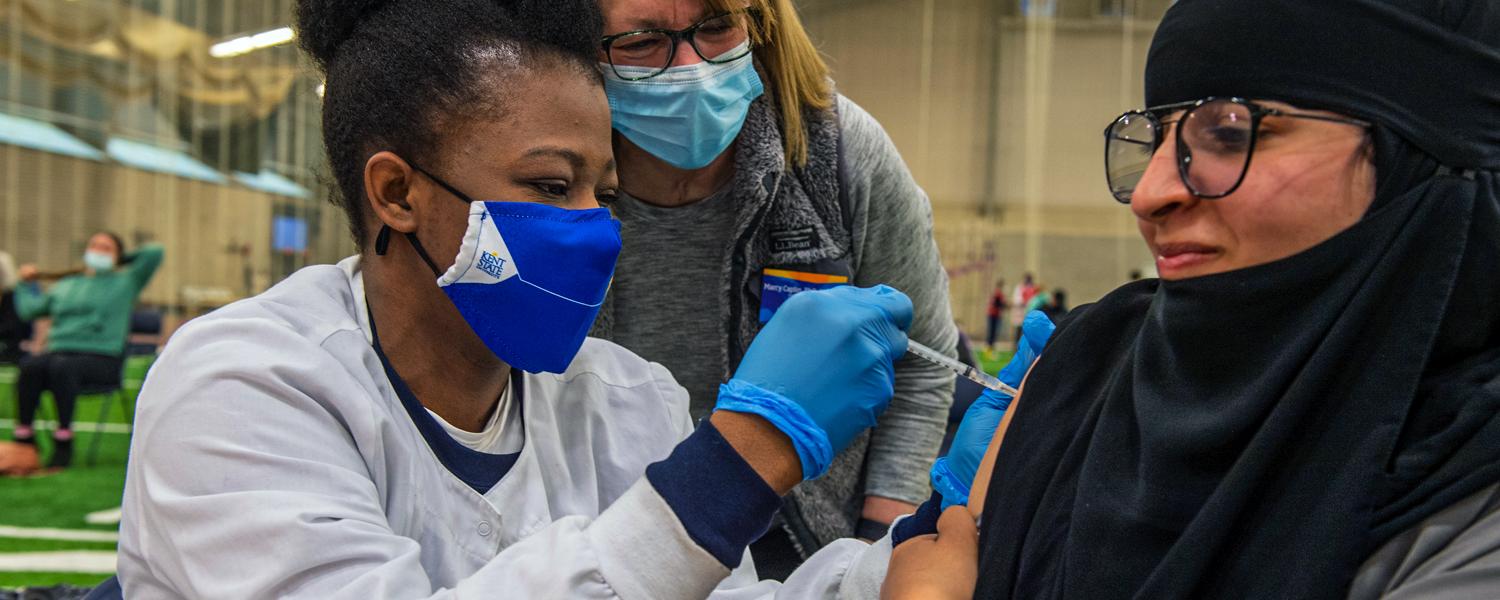 A Kent State nursing student administers a COVID-19 vaccine into a Kent State Community Member's arm.