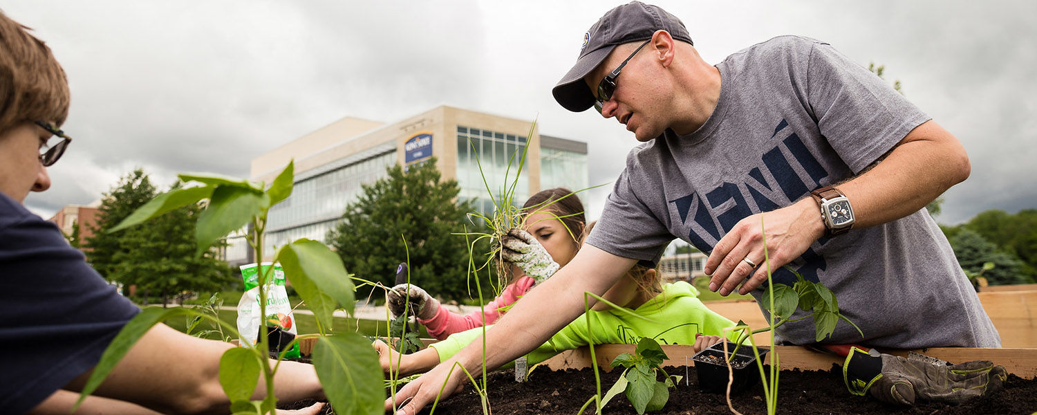 Chris Post, Ph.D., associate professor of geography, works with others on the Kent State University at Stark campus garden.