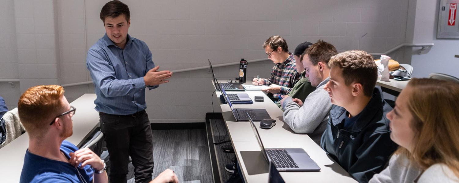 Professor instructing students with computers