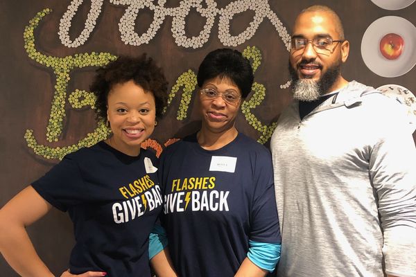 Alumni wearing Flashes Give Back tshirts, smiling, participating at a local Food Bank