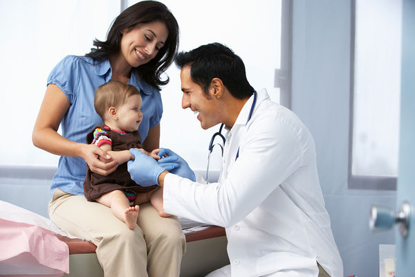 A male Pediatric Nurse Practitioner examines a baby who is sitting in her mother's lap