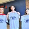 Two male and one female students holding up Kent State t-shirts