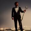 picture of Gospel tenor David Phelps dressed in black tie suit holding a microphone with stand wrapped in white lights